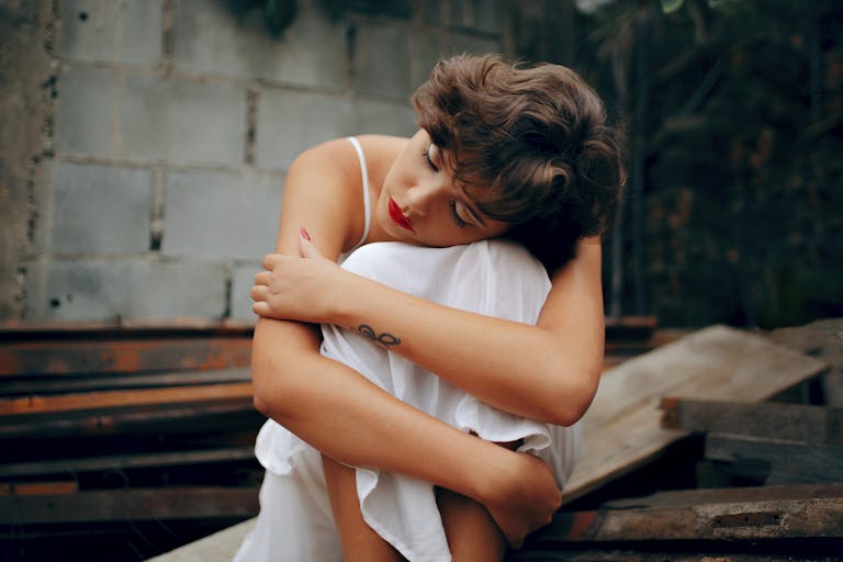 A woman in a white dress sits alone, conveying solitude and introspection.