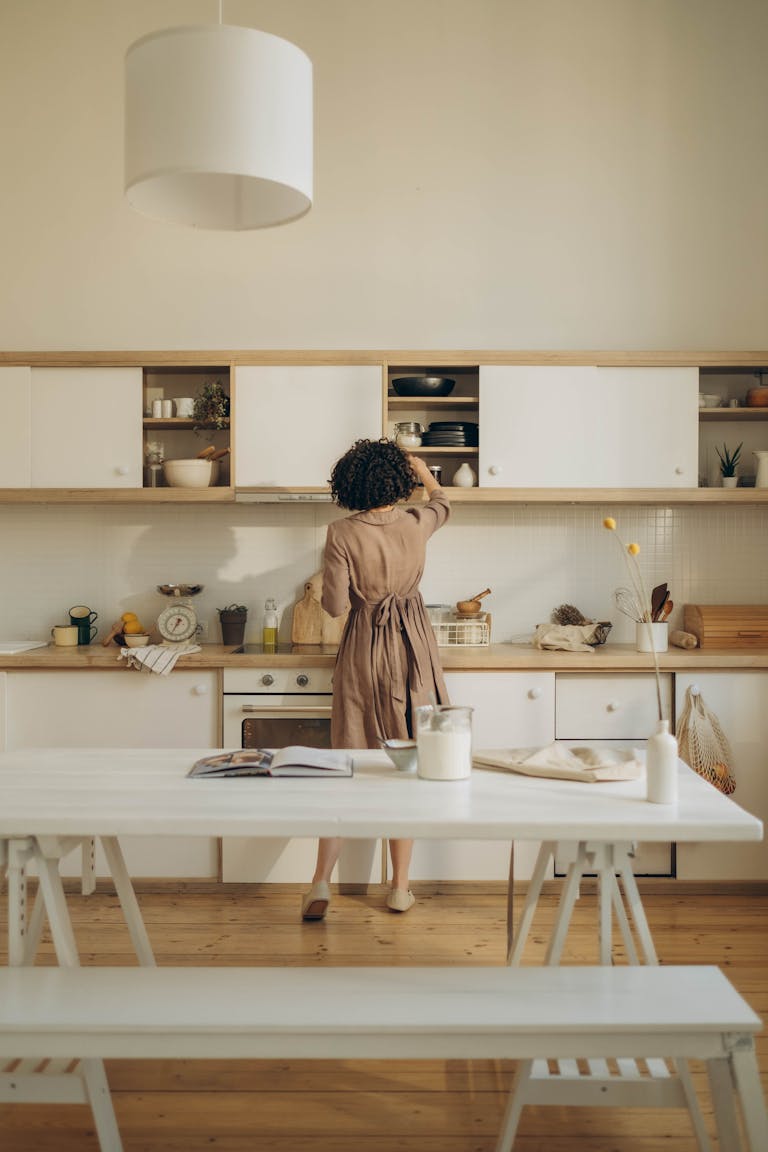 African American woman organizing kitchen cabinets in a modern minimalist style kitchen.