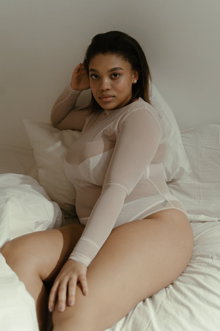Confident plus size woman posing indoors, embracing body positivity in neutral tones.