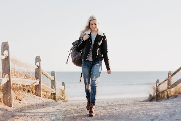 Stylish woman in leather jacket walking by the ocean in Ocean City, NJ.