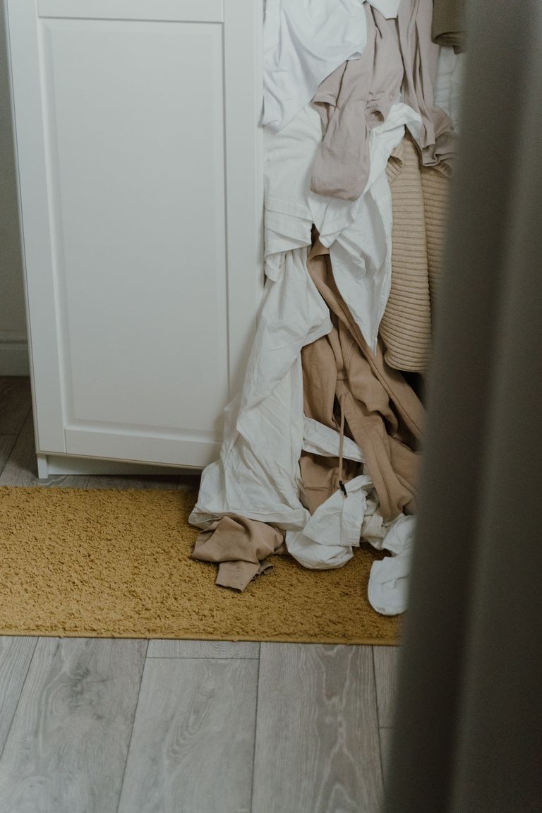 A cluttered wardrobe with clothes spilling onto the floor, reflecting fast fashion impact.